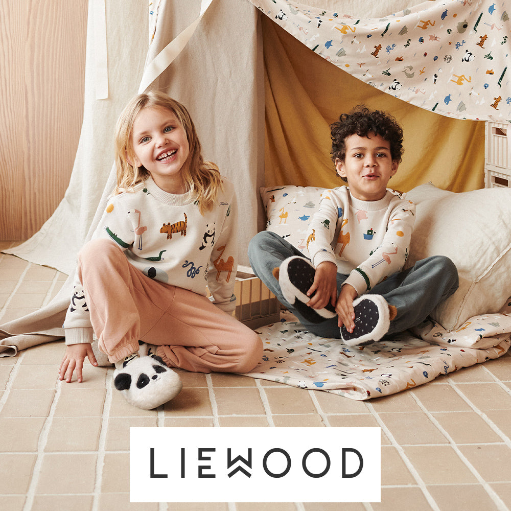 Image of a two children playing in a blanket fort alongside the Liewood logo