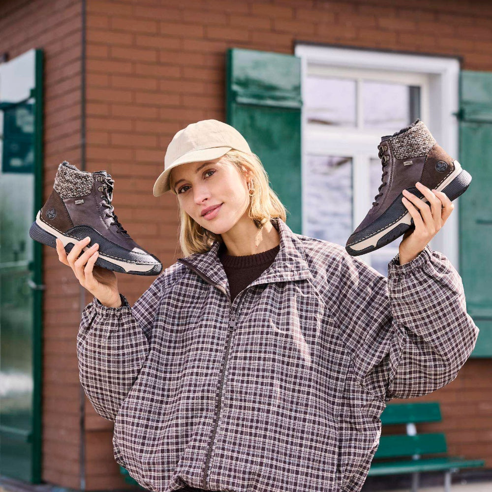 woman holding up a pair of brown boots